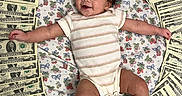 Melody is registered to the contest to win money with this photo: baby, infant, money, dollar_bills, circle, blanket, floral_pattern, striped_onesie, smiling, cute, happy, lying_down, arms_outstretched, curly_hair, indoors, person, child, currency, cash, playful