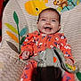 baby, child, smiling, onesie, floral_pattern, baby_chair, animal_print, happy, infant, seat_belt, indoor, cute, playful, colorful, comfort, portrait, person, young_child, seat, joyful