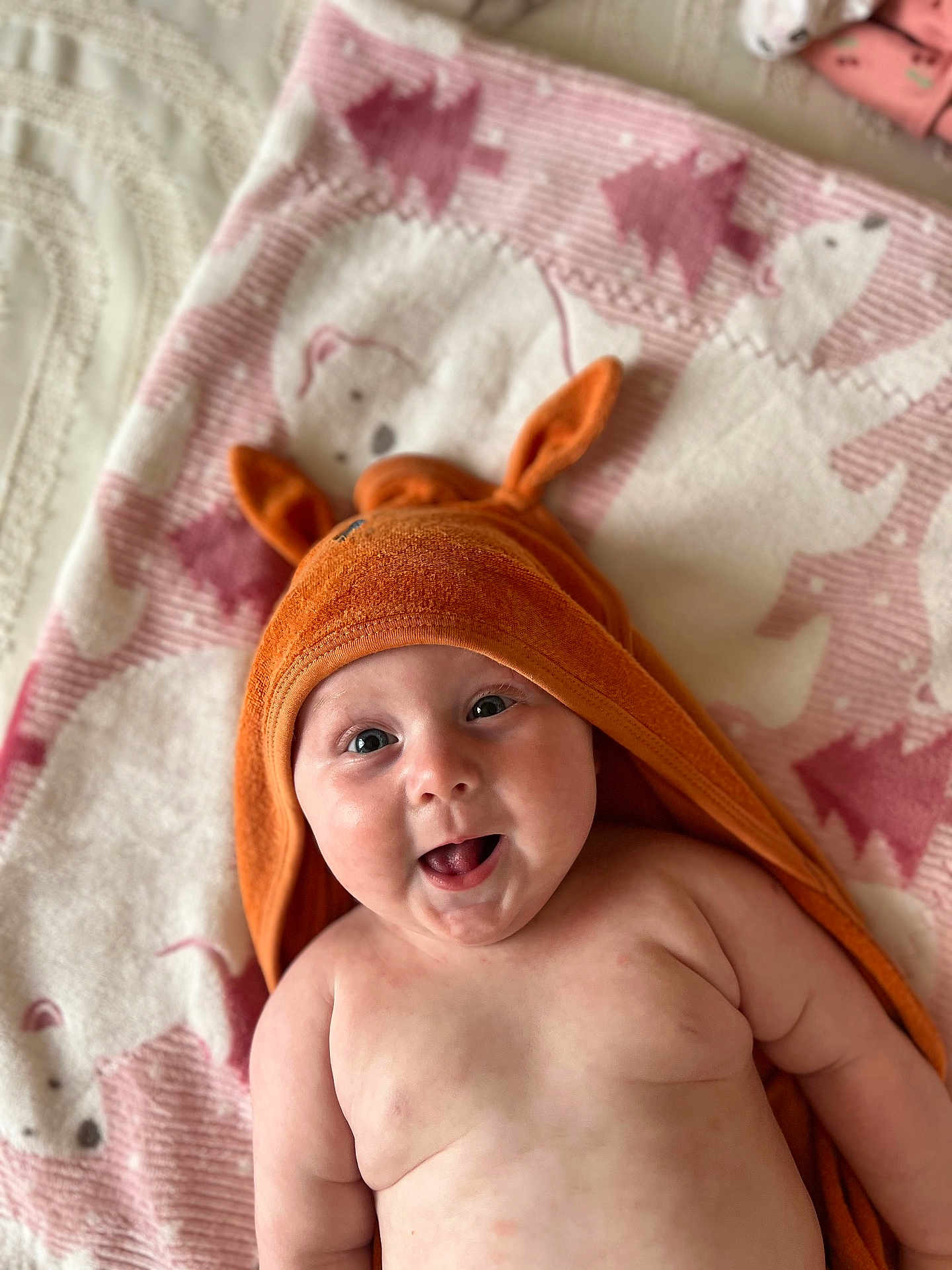 Eva joined the competition — help win amazing prizes! baby, infant, smiling, orange_towel, hooded_towel, cute, blanket, polar_bear_pattern, pink, happy, chubby_cheeks, lying_down, indoors, soft_texture, child, skin, face, eyes, mouth, playful