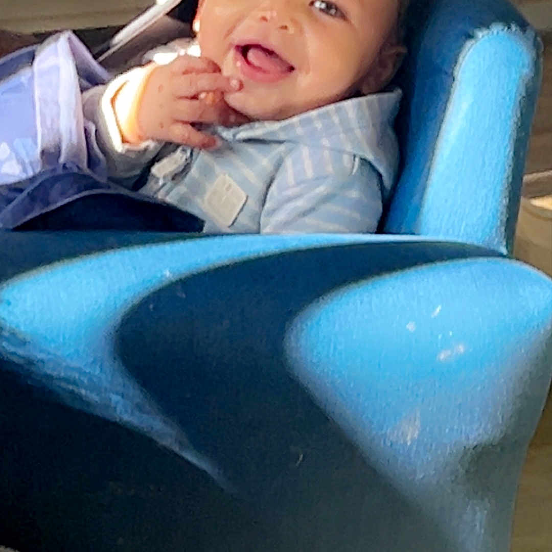 Kevin is registered to the contest to win money with this photo: baby, baseballcap, beverage, cap, chair, clothing, coat, coffee, coffeecup, couch, face, furniture, happy, hat, head, jacket, pants, person, photography, portrait