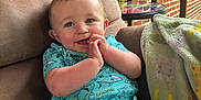 Mason is registered to the contest to win money with this photo: baby, child, smiling, blue_outfit, shark_pattern, cushioned_chair, blanket, brick_wall, porch, wooden_railing, happy, face, hands, sitting, indoor, cute, infant, clothing, comfort, portrait