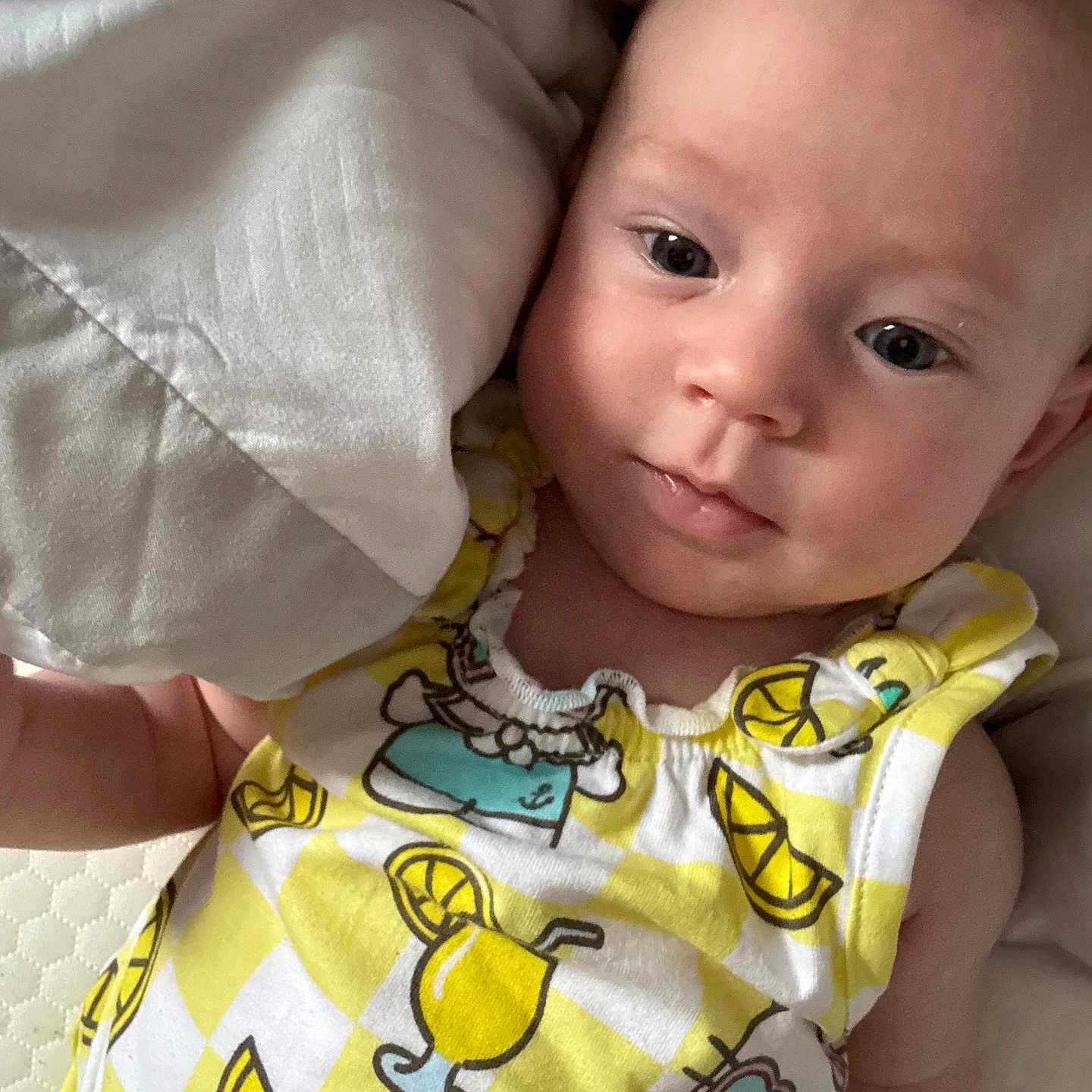 Khloe is registered to the contest to win money with this photo: baby, infant, face, eyes, blanket, clothing, yellow, pattern, drink, lemon, cute, portrait, lying_down, child, skin, expression, soft_light, indoors, young, person
