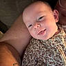 Khloe is registered to the contest to win money with this photo: baby, child, smile, face, arm, tattoo, floral_clothing, person, skin, closeup, infant, cute, expression, holding, portrait, indoors, warm_light, human, head, happy
