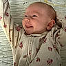 Khloe is registered to the contest to win money with this photo: baby, smile, infant, onesie, floral_pattern, tongue_out, happy, cute, child, lying_down, face, skin, head, ear, clothing, texture, fabric, pattern, background, portrait