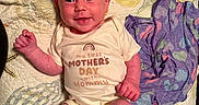 Khloe joined the competition — help win amazing prizes! baby, infant, smile, onesie, quilt, seashell_pattern, clothing, purple_garment, happy, lying_down, cute, newborn, celebration, indoor, child, fabric, pattern, toddler, person, portrait