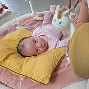 Raya Louisa Gyoch participe au concours pour gagner de l'argent avec cette photo : baby, pillow, plush_toy, unicorn, blanket, infant, toy, floor, carpet, person, pink_clothing, indoor, head, face, looking, soft_toys, child, home, resting, cushion