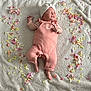 baby, newborn, infant, sleeping, pink_outfit, headwrap, blanket, flower_petals, top_view, textured_blanket, soft_lighting, cute, toes, hands, portrait, lying_down, studio_style, pale_skin, small_size, cozy