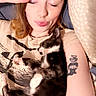 person, kitten, cat, sleeping, cuddling, tattoo, peace_sign, bed, pillow, relaxing, indoor, closeup, hair, face, skin, animal, cute, young_adult, casual, comfort