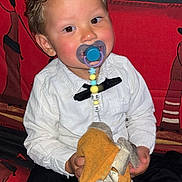 Lyann a rejoint le concours — aidez-le/la à gagner de superbes lots ! toddler, child, pacifier, white_shirt, black_bow_tie, curly_hair, orange_cloth, tags, couch, patterned_couch, indoor, sitting, cute, holding, clothing, person, face, baby, adorable, young_child