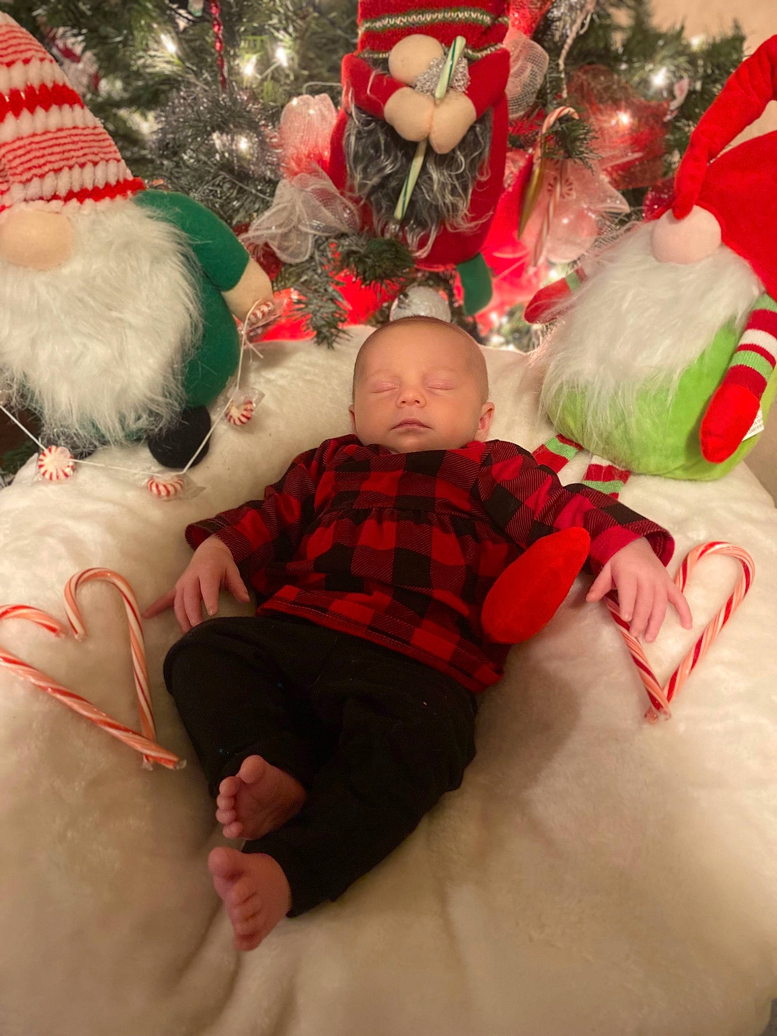 Layana is registered to the contest to win money with this photo: baby, christmas, christmas_decoration, christmas_eve, christmas_ornament, christmas_tree, comfort, event, face, fun, happy, holiday, holiday_ornament, human_body, lap, leg, ornament, person, red, toddler