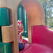 Everleigh is registered to the contest to win money with this photo: child, girl, playground, slide, outdoor, smiling, pink_bow, jeans, tank_top, daylight, trees, park, play_equipment, fun, cute, happy, nature, sunny, recreation, leisure
