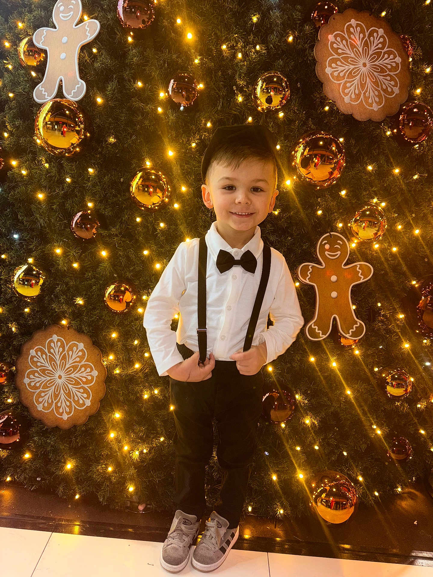 Saymon participe au concours pour gagner de l'argent avec cette photo : child, boy, smiling, christmas_tree, lights, gingerbread_cookie, baubles, holiday, festive, suspenders, bow_tie, white_shirt, black_pants, shoes, indoor, decorations, celebration, portrait, happy, fashion