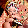 baby, bodypart, bonnet, cap, clothing, couch, cutlery, doll, face, finger, furniture, hand, hat, head, newborn, person, photography, portrait, spoon, toy