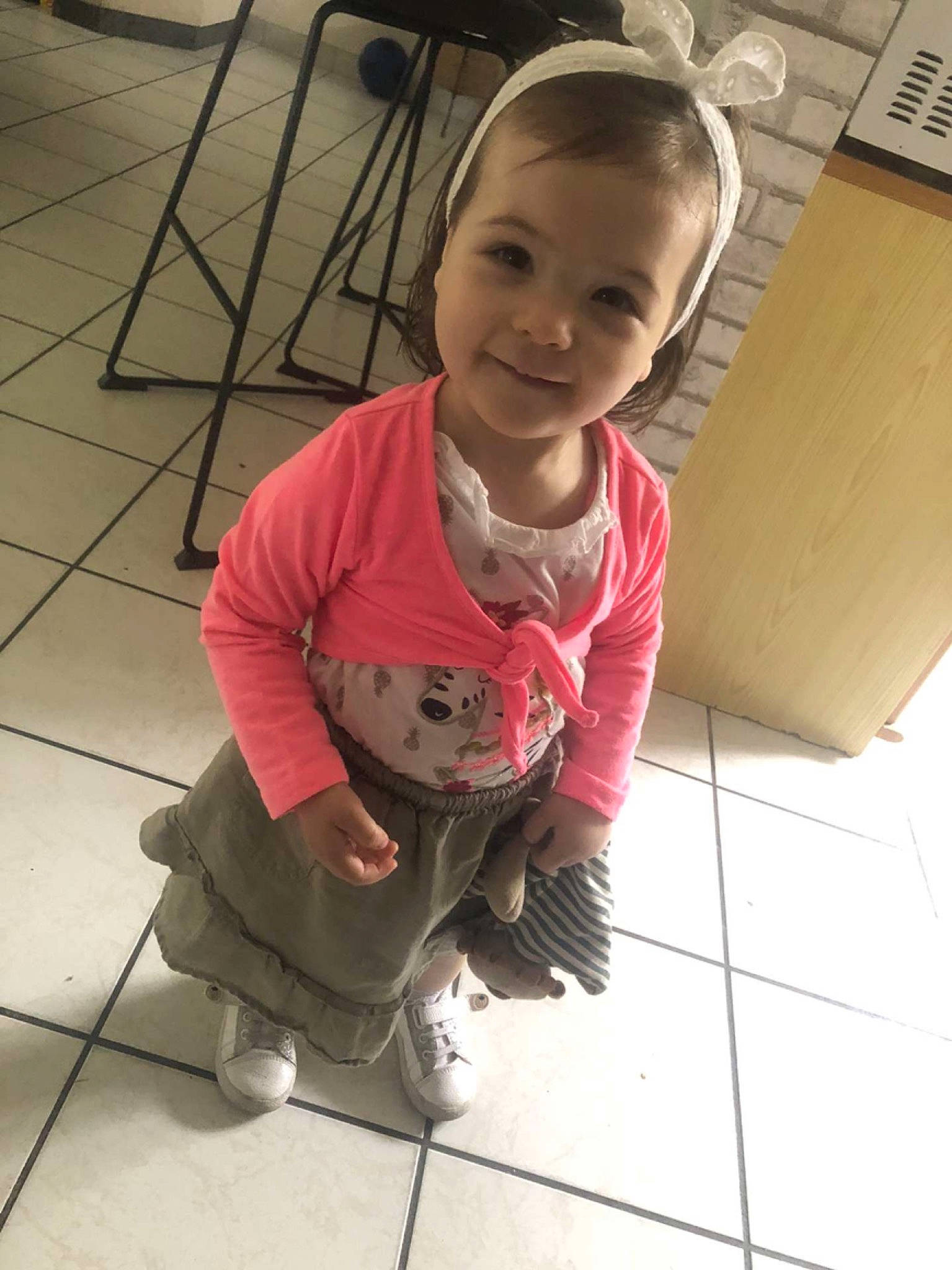 Mia a rejoint le concours — aidez-le/la à gagner de superbes lots ! baby_toddler_clothing, chair, cheek, child, face, floor, flooring, foot, happy, hardwood, human_leg, joy, person, pink, shoe, sitting, skin, sleeve, smile, thigh