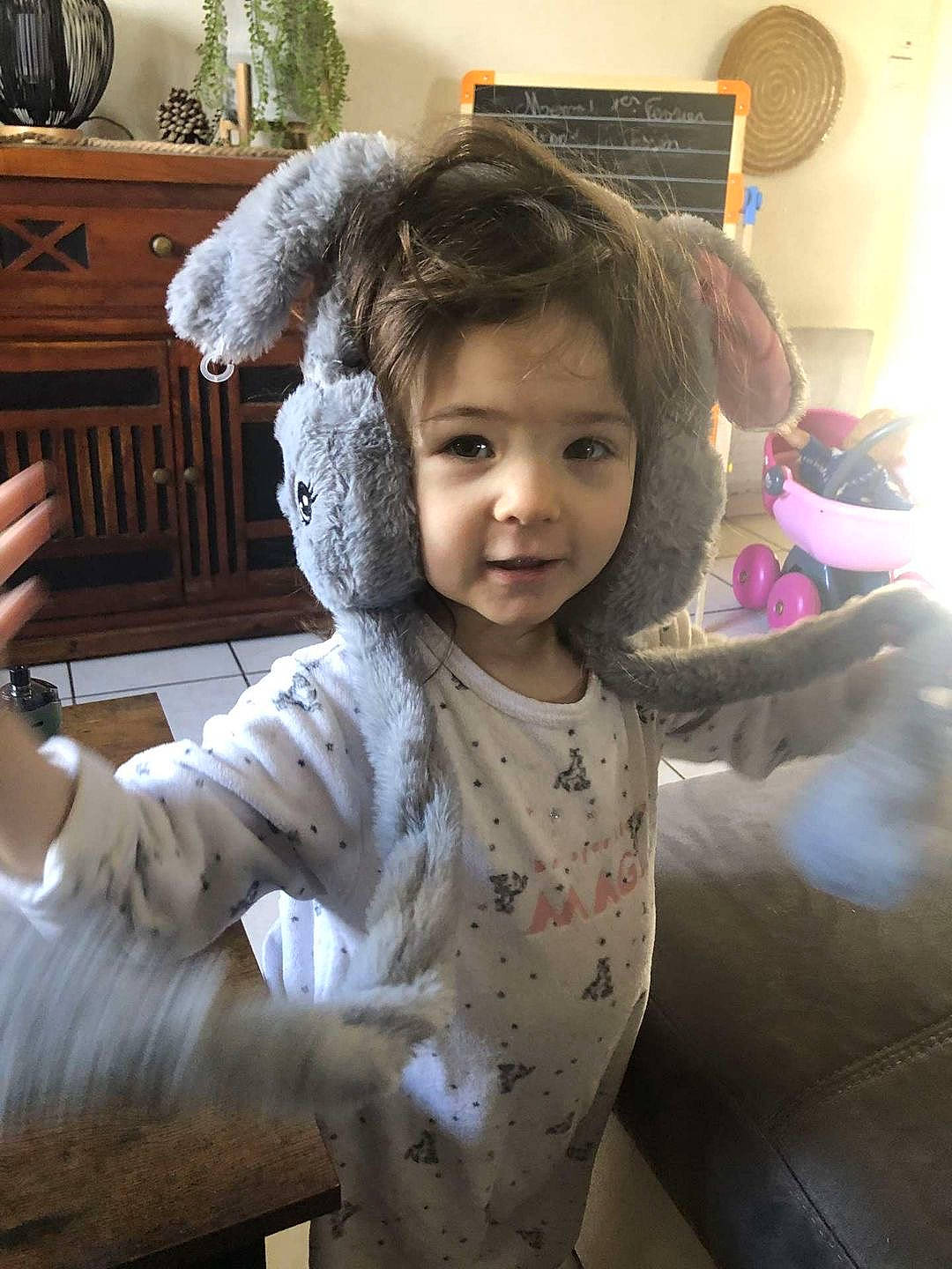 Mia participe au concours pour gagner de l'argent avec cette photo : arm, baby_toddler_clothing, chair, cheek, child, facial_expression, finger, fun, fur, gesture, happy, person, picture_frame, room, sitting, skin, sleeve, smile, standing, thumb