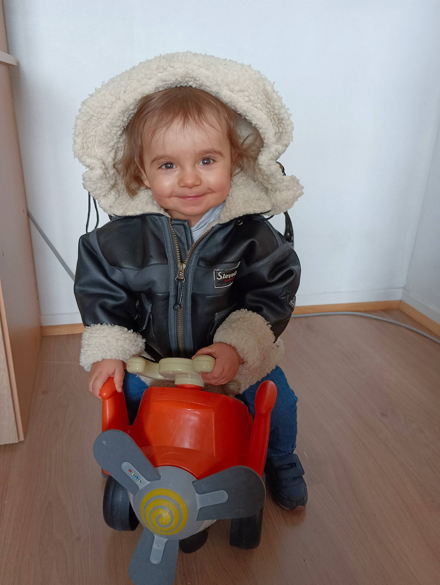 Caleb a rejoint le concours — aidez-le/la à gagner de superbes lots ! baby, baby_toddler_clothing, cap, child, fashion_accessory, flooring, fun, hardwood, hat, joy, lap, person, play, riding_toy, sitting, sleeve, smile, sun_hat, toddler, toy