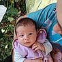 arm, baby, butterfly_patch, casual, child, closeup, curious_expression, face, greenery, hand, holding, human, infant, nature, outdoor, person, plants, portrait, purple_clothing, young