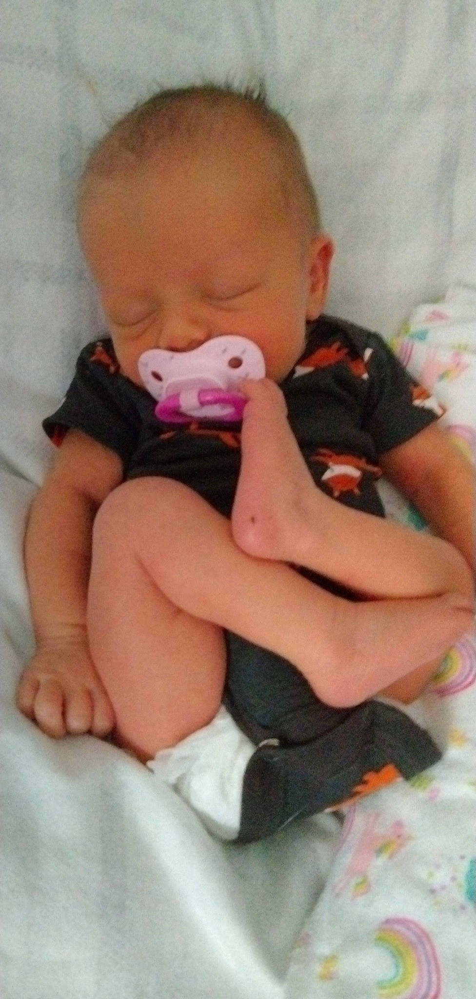 Natalia is registered to the contest to win money with this photo: arm, baby, baby_toddler_clothing, cheek, child, comfort, finger, human_body, knee, leg, mouth, neck, person, pink, product, skin, sleeve, sock, textile, thigh