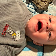 Julius is registered to the contest to win money with this photo: baby, infant, face, smile, clothing, sweater, peanuts, cartoon, blanket, soft, cute, child, portrait, happy, indoors, skin, head, eyes, mouth, expression