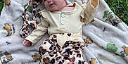 April joined the competition — help win amazing prizes! baby, blanket, outdoor, grass, infant, clothing, pattern, headband, cute, lying_down, teddy_bear_pattern, nature, child, soft_texture, foot, hand, smile, person, apparel, relaxing