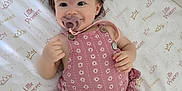 Camila is registered to the contest to win money with this photo: baby, infant, pacifier, pink_romper, crown_pattern, crib_mattress, little_princess_text, child, cute, smiling, lying_down, indoors, soft_lighting, toddler, hand, foot, hair, skin, clothing, playful