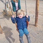 Jazmine is registered to the contest to win money with this photo: boots, chain, child, dirt, fence, glasses, hair, jacket, jeans, outdoors, play, playground, portrait, rural, shadow, sibling, smile, sunny, swing, wood_post