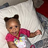 toddler, child, smiling, bed, pillow, hair_puffs, clothing, tattoo, person, hand, skin, happy, indoor, casual, cute, baby, holding, infant, portrait, person_holding_child