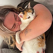 Fluffy participe au concours pour gagner de l'argent avec cette photo : person, cat, calico_cat, glasses, tattoo, butterfly_tattoo, hugging, indoor, couch, affection, pet, animal, love, casual_clothing, light_hair, closeup, comfort, relaxation, home, furniture