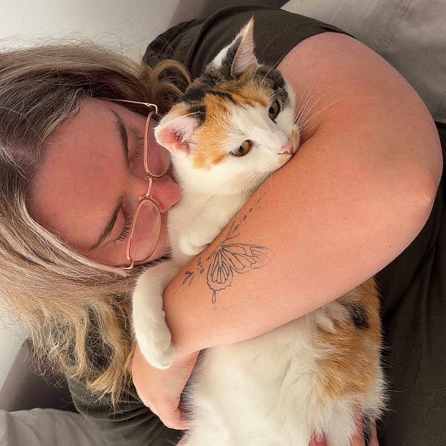Fluffy participe au concours pour gagner de l'argent avec cette photo : person, cat, calico_cat, glasses, tattoo, butterfly_tattoo, hugging, indoor, couch, affection, pet, animal, love, casual_clothing, light_hair, closeup, comfort, relaxation, home, furniture