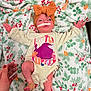 Hadley is registered to the contest to win money with this photo: baby, infant, headband, bow, medical_tubes, blanket, floral_pattern, onesie, hand, nail_polish, hospital, newborn, lying_down, cute, child, person, skin, small, indoors, soft