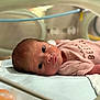 newborn, baby, incubator, hospital, medical_tube, pink_clothing, infant, lying_down, medical_equipment, patient, nasal_cannula, face, head, child, healthcare, premature_baby, hospital_bed, blanket, closeup, person