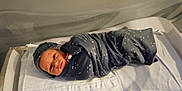 Kaiden joined the competition — help win amazing prizes! newborn, baby, swaddled, blanket, hospital, bassinet, infant, face, person, bed, sleepwear, cute, cozy, resting, indoors, portrait, young, child, wrapped, sleeping_area