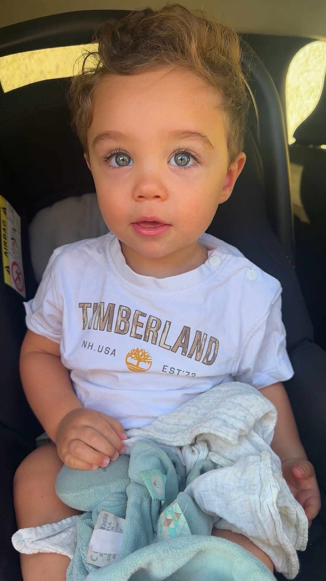 Ghjuvan-Andria participe au concours pour gagner de l'argent avec cette photo : toddler, child, car_seat, blanket, plush_toy, blue_eyes, timberland_tshirt, casual_clothing, indoor, portrait, baby, cute, hands, soft_toys, comfort, seated, expression, close_up, natural_light, young_child
