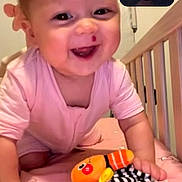 Hope joined the competition — help win amazing prizes! baby, child, smiling, pink_clothing, crib, toy, plush_toy, crawling, happy, indoor, bed, animal_print, face, person, video_call, woman, adult, closeup, home, joy