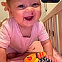 baby, child, smiling, pink_clothing, crib, toy, plush_toy, crawling, happy, indoor, bed, animal_print, face, person, video_call, woman, adult, closeup, home, joy