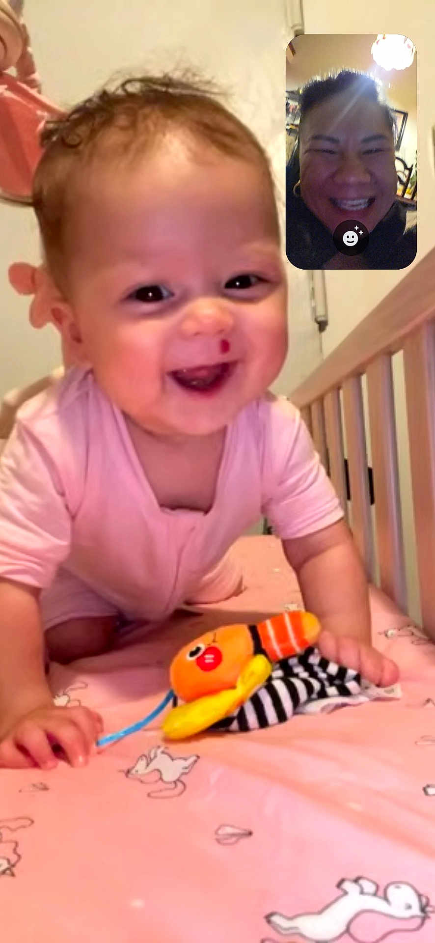 Hope joined the competition — help win amazing prizes! baby, child, smiling, pink_clothing, crib, toy, plush_toy, crawling, happy, indoor, bed, animal_print, face, person, video_call, woman, adult, closeup, home, joy