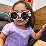 toddler, child, sunglasses, unicorn, purple_top, indoor, cute, fashion, playful, curious, person, short_hair, wood_paneling, tattoo, seated, accessory, colorful, fun, portrait, young