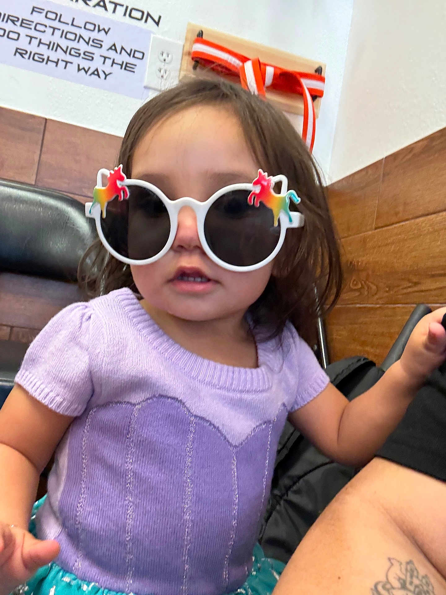 Amelia is registered to the contest to win money with this photo: toddler, child, sunglasses, unicorn, purple_top, indoor, cute, fashion, playful, curious, person, short_hair, wood_paneling, tattoo, seated, accessory, colorful, fun, portrait, young