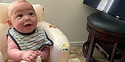 Tyree joined the competition — help win amazing prizes! baby, infant, bib, inflatable_seat, dinosaur_pattern, striped_clothing, smiling, curious, indoor, floor, television, furniture, carpet, wall, seat, child, person, happy, cute, home