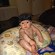 Allen joined the competition — help win amazing prizes! baby, child, hat, pillow, diaper, hand, foot, face, skin, sitting, blanket, animal_print, indoor, home, curious, expression, cute, infant, childhood, comfort