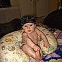 baby, child, hat, pillow, diaper, hand, foot, face, skin, sitting, blanket, animal_print, indoor, home, curious, expression, cute, infant, childhood, comfort
