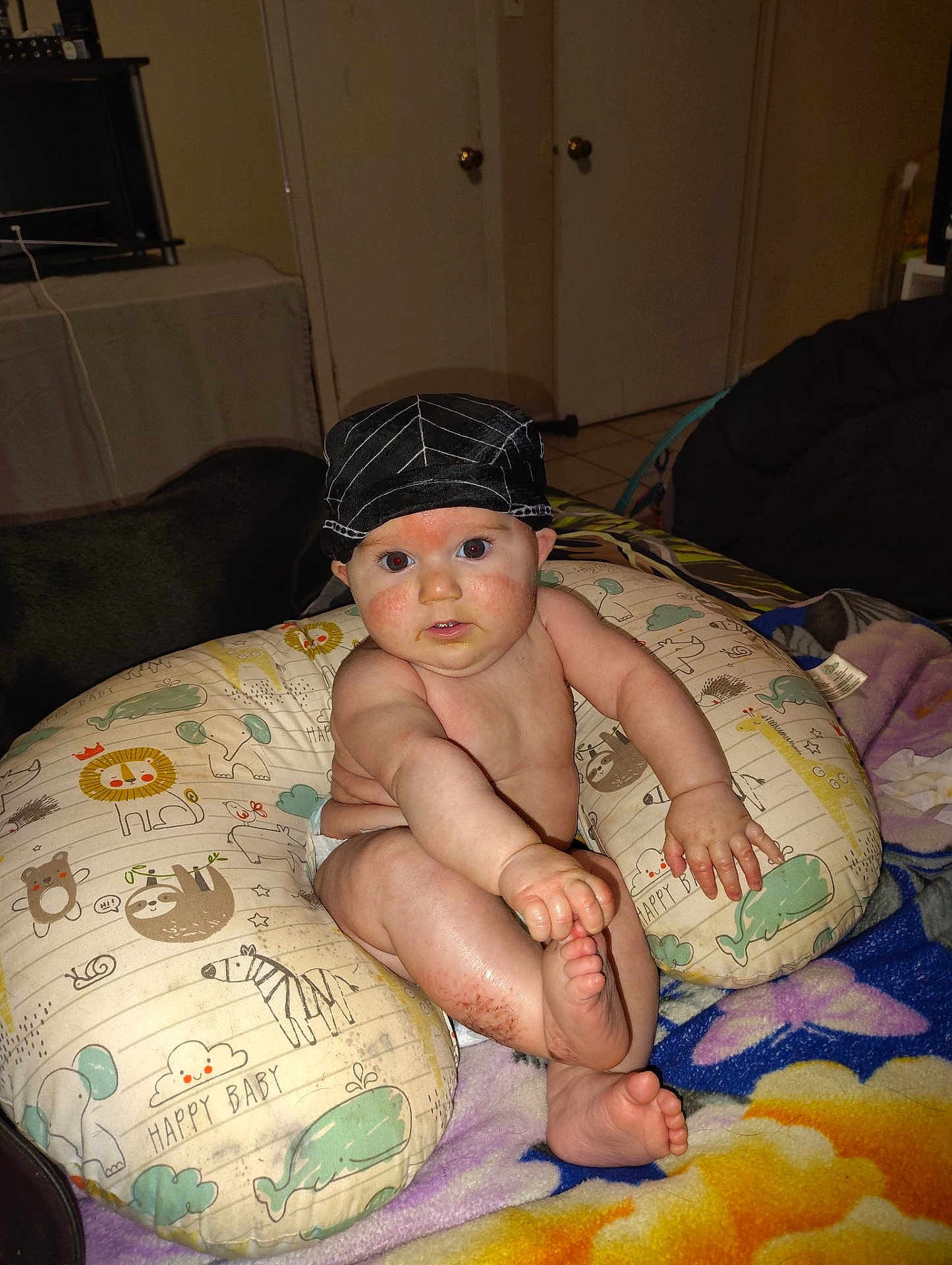 Allen joined the competition — help win amazing prizes! baby, child, hat, pillow, diaper, hand, foot, face, skin, sitting, blanket, animal_print, indoor, home, curious, expression, cute, infant, childhood, comfort
