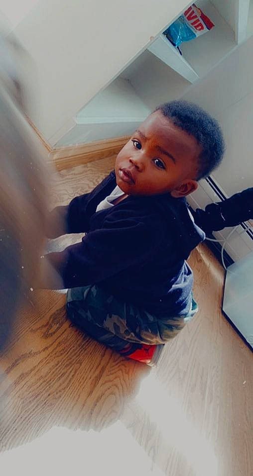 He'Zekiah is registered to the contest to win money with this photo: chin, comfort, elbow, eyebrow, facial_expression, floor, flooring, fun, happy, hardwood, leg, mouth, neck, nose, person, skin, sleeve, standing, t_shirt, toddler