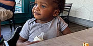 Jiayze is registered to the contest to win money with this photo: baby_bottle, background, casual_clothing, chair, child, crumbs, curly_hair, high_chair, indoor, light, man, person, restaurant, seated, table, thoughtful, toddler, wall, window, wooden_floor
