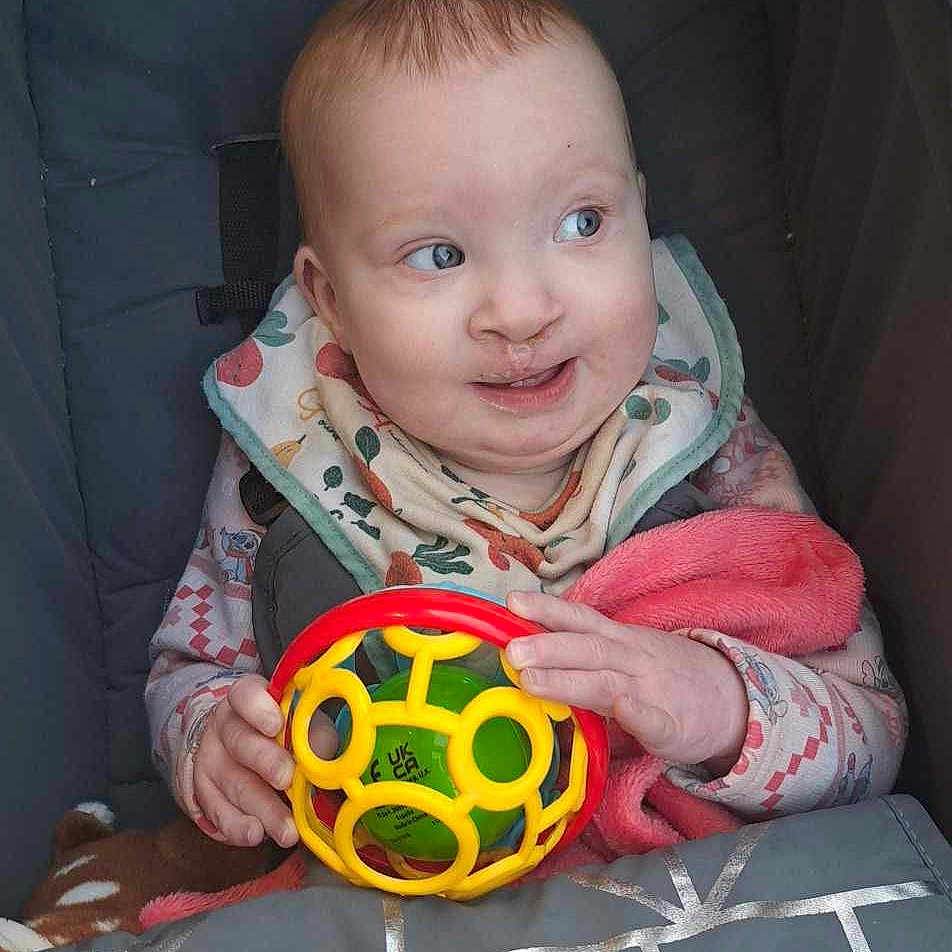 Ava-Mae is registered to the contest to win money with this photo: baby, ball, blanket, clothing, coat, couch, cushion, face, football, furniture, head, homedecor, jacket, person, photography, portrait, soccer, soccerball, sport, toy