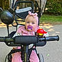 Jade a rejoint le concours — aidez-le/la à gagner de superbes lots ! baby, child, pacifier, pink_headband, stroller, tricycle, outdoor, park, trees, sunlight, path, toy, handlebars, wheel, clothing, cute, infant, person, nature, daytime