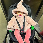 Jade participe au concours pour gagner de l'argent avec cette photo : baby, stroller, pacifier, pink_clothing, hooded_jacket, footed_pants, infant, indoor, elevator, metallic_walls, black_stroller, child, seat_belt, curious, wide_eyes, soft_texture, warm_clothing, person, cute, infant_care
