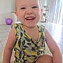 toddler, child, smiling, happy, indoor, playful, lemon_pattern, clothing, person, face, young, cute, sitting, floor, tile_floor, ball, purple_ball, sunlight, window_blinds, home