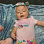 baby, infant, headband, pink_shirt, floral_pants, blanket, patterned_blanket, lying_down, cute, child, smiling, happy, indoor, portrait, person, clothing, colorful, small_child, baby_girl, soft_texture