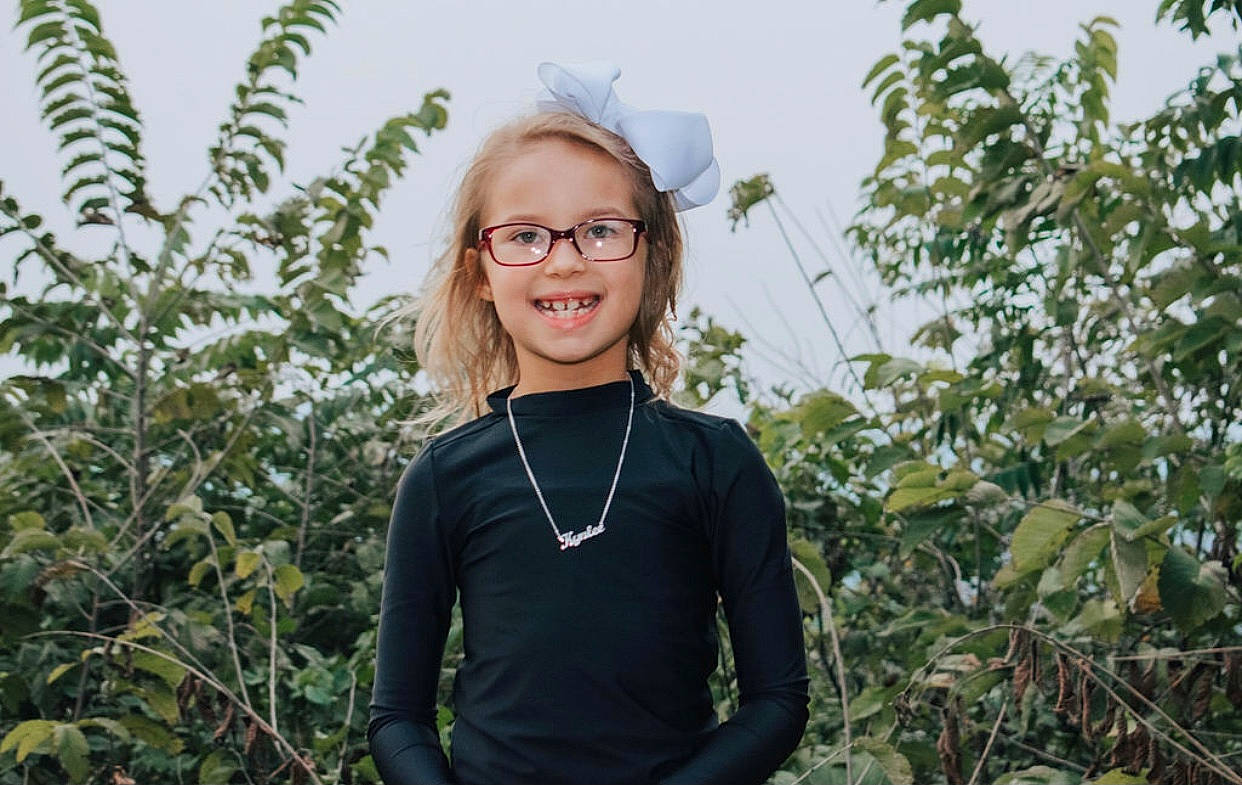 Kynlee is registered to the contest to win money with this photo: adaptation, botany, eyewear, flower, fun, glasses, grass, happy, joy, organism, person, photography, plant, portrait, smile, tree, vision_care